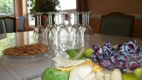 A table with a platter of grapes, cheese, and crackers, and a row of inverted wine glasses